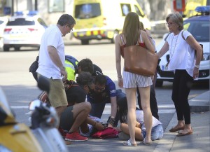 An injured person is treated in Barcelona, Spain, Thursday, Aug. 17, 2017 after a white van jumped the sidewalk in the historic Las Ramblas district, crashing into a summer crowd of residents and tourists and injuring several people, police said. (AP Photo/Oriol Duran)